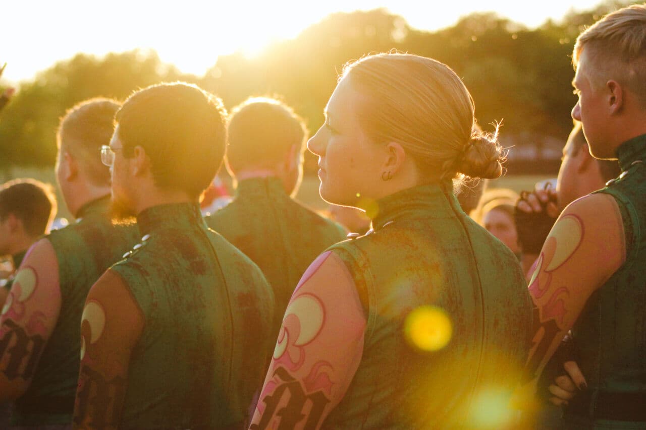 Golden-hour silhouette of Emma and fellow corps members between sets