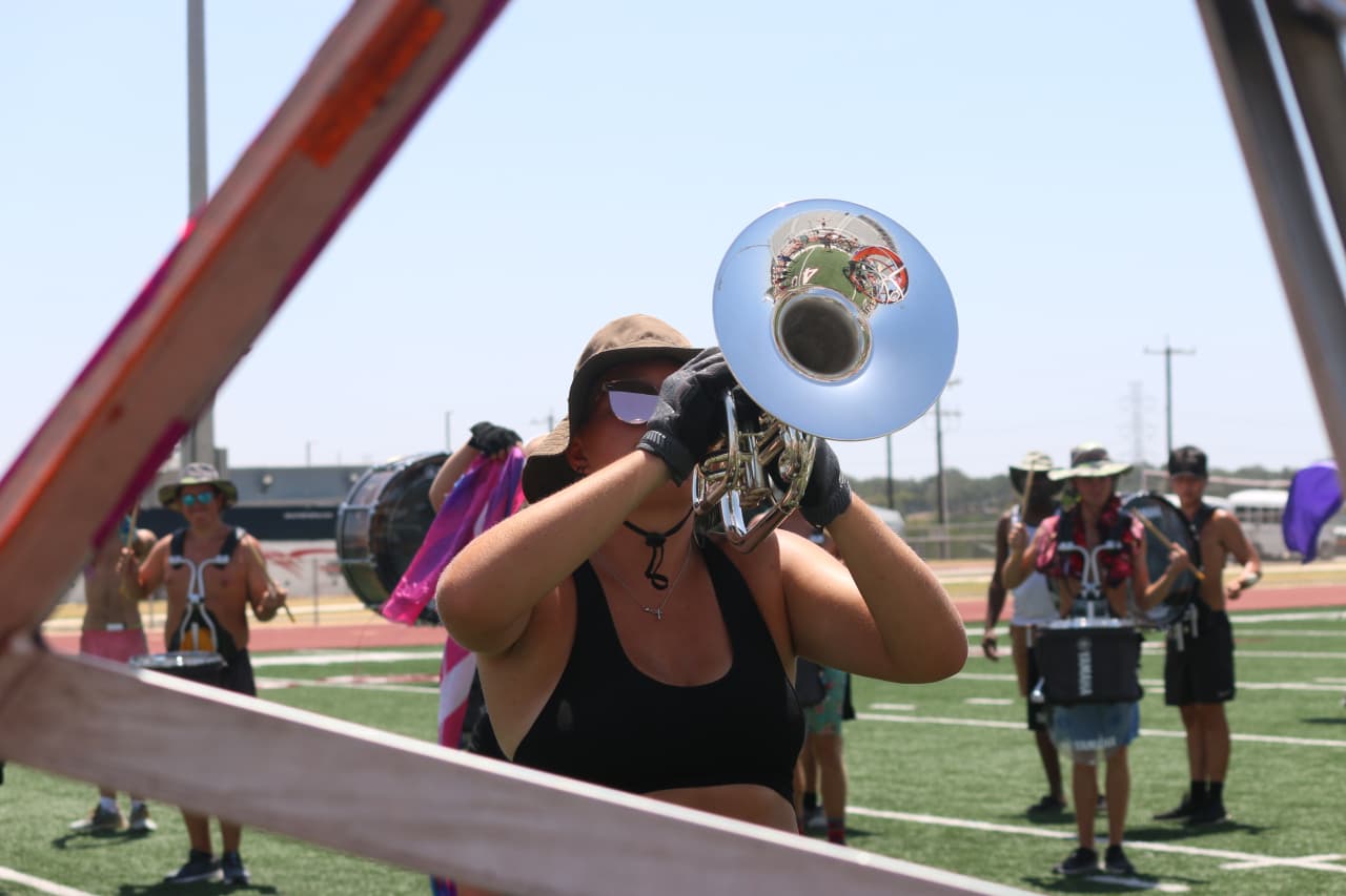 Emma playing mellophone during a rehearsal with corps members behind her