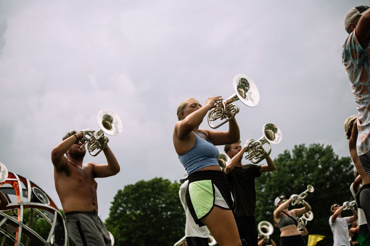 Low-angle view of the brass section rehearsing against an overcast sky