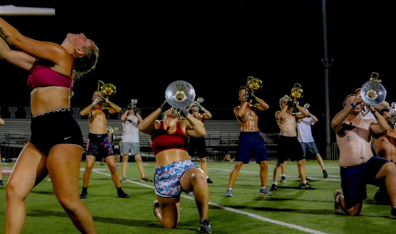 Late-night brass rehearsal on the football field under stadium lights